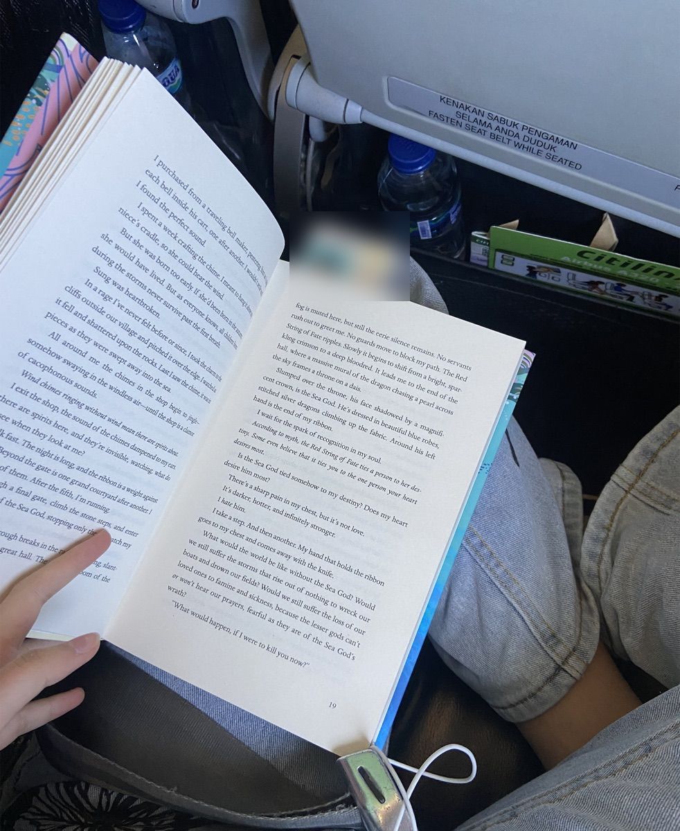 An open novel on my lap during a flight
